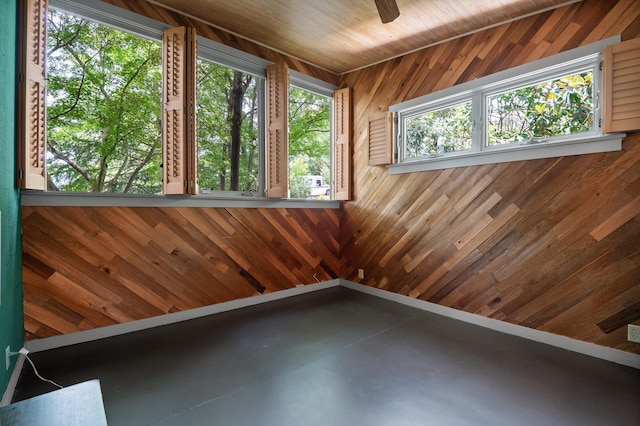 2554 Crestwood Dr, Chattanooga, TN 37415 - spare room featuring concrete floors, wood walls, and a ceiling fan