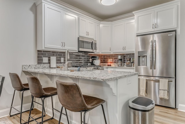 320 Kempton Ln Unit 2, Dalton, GA 30721 - kitchen with stainless steel appliances, a peninsula, tasteful backsplash, white cabinets, and light wood-style flooring