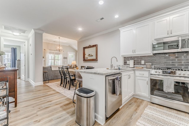 320 Kempton Ln Unit 2, Dalton, GA 30721 - kitchen with stainless steel appliances, ornamental molding, a peninsula, white cabinetry, and light wood-type flooring