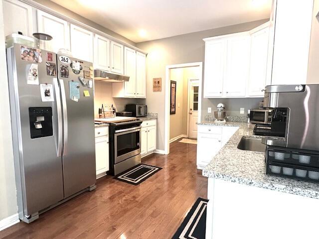8041 Hamilton Mill Dr, Chattanooga, TN 37421 - kitchen with appliances with stainless steel finishes, dark wood-type flooring, under cabinet range hood, white cabinets, and light stone countertops