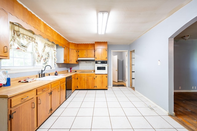 7635 Austin Dr, Chattanooga, TN 37416 - kitchen featuring black appliances, light countertops, under cabinet range hood, backsplash, and brown cabinetry