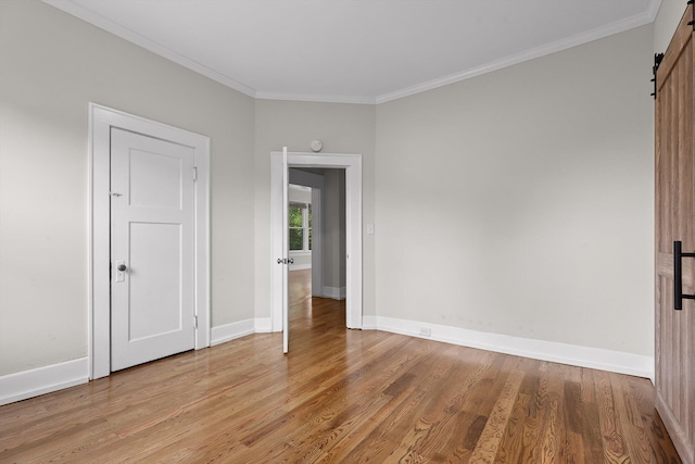 6863 Standifer Gap Rd, Chattanooga, TN 37421 - unfurnished bedroom featuring a barn door, light wood-type flooring, and crown molding