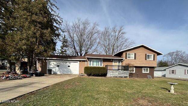 tri-level home featuring a garage and a front lawn