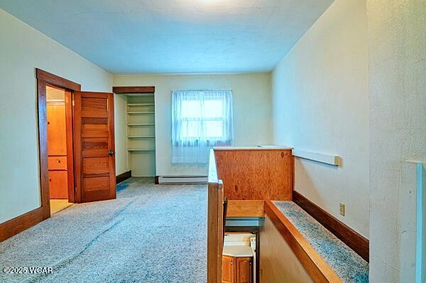 bedroom with light carpet and baseboard heating