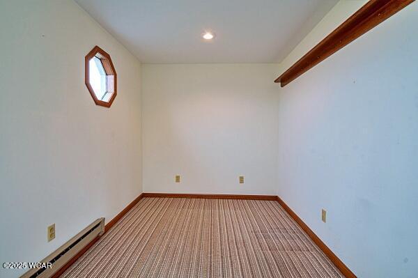 empty room featuring baseboard heating and light colored carpet