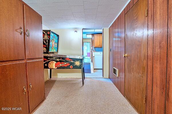 hallway featuring washer / clothes dryer and light carpet