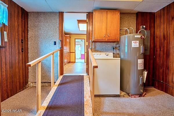 kitchen featuring wooden walls, electric water heater, a drop ceiling, washer / clothes dryer, and light carpet