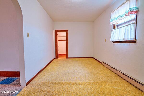 unfurnished room with carpet floors and a baseboard heating unit