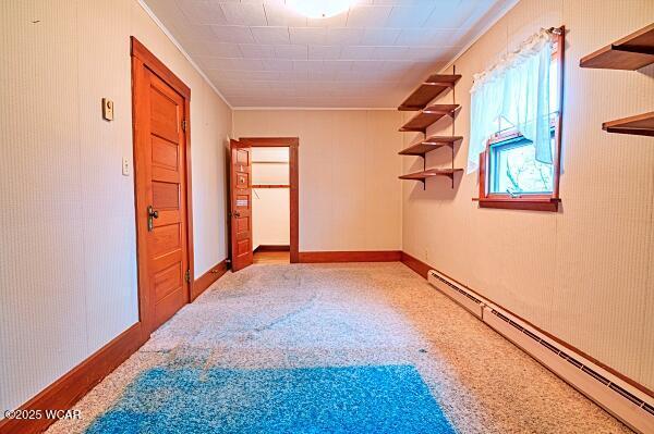 carpeted empty room with a baseboard radiator