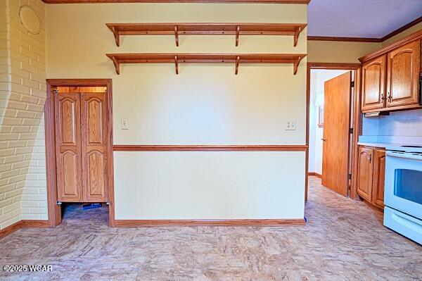 kitchen featuring a kitchen bar, crown molding, electric stove, light colored carpet, and backsplash