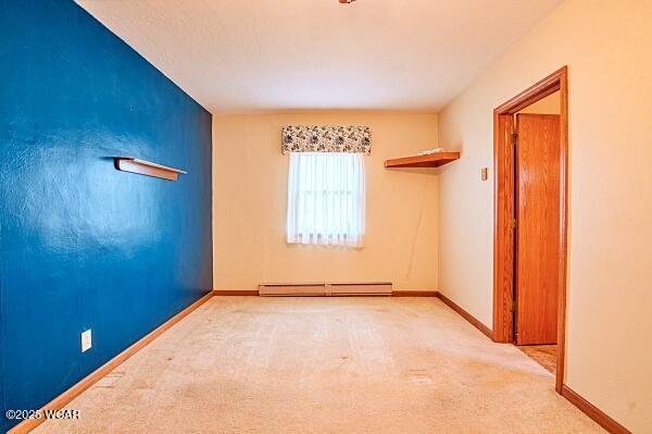 spare room with a baseboard radiator and light colored carpet