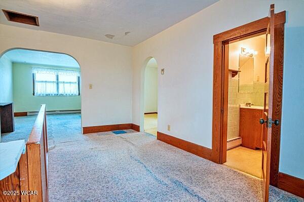 empty room featuring light colored carpet and a baseboard radiator