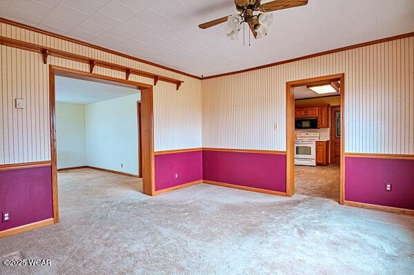 empty room featuring ceiling fan, ornamental molding, and light carpet