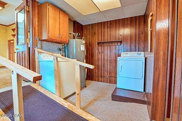 clothes washing area with washer / clothes dryer, carpet floors, wooden walls, and water heater