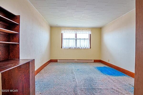 empty room with carpet flooring, ornamental molding, and baseboard heating