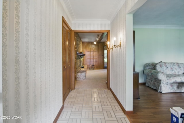 hall featuring wallpapered walls, wood finished floors, crown molding, and baseboards