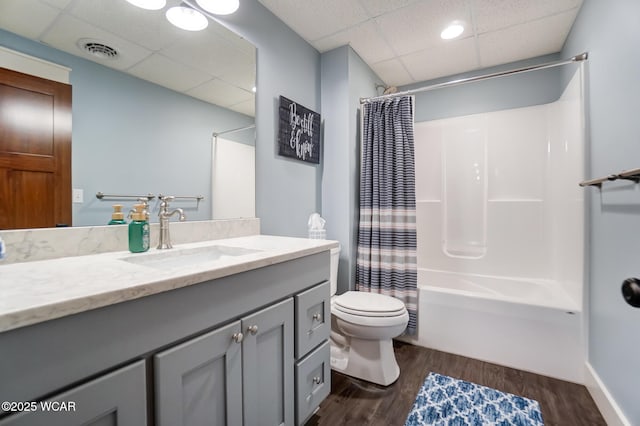 full bathroom featuring shower / tub combo with curtain, hardwood / wood-style flooring, vanity, toilet, and a drop ceiling