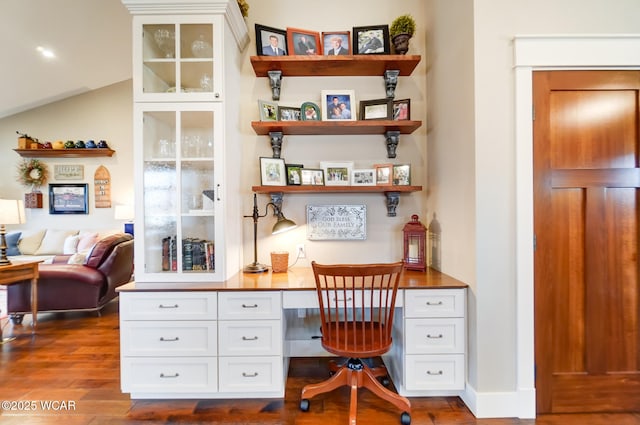 home office featuring vaulted ceiling, dark hardwood / wood-style floors, and built in desk