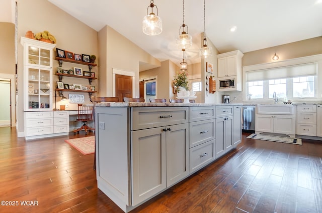 kitchen with gray cabinets, vaulted ceiling, appliances with stainless steel finishes, decorative light fixtures, and sink