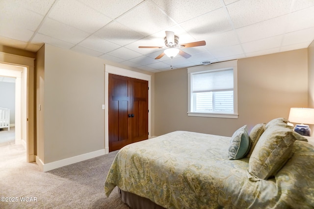 carpeted bedroom with ceiling fan and a drop ceiling