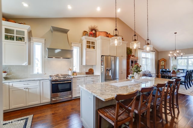 kitchen with stainless steel appliances, custom range hood, white cabinets, and a kitchen island