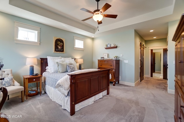 bedroom featuring light colored carpet, a raised ceiling, and ceiling fan