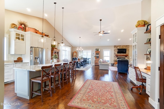 kitchen with a breakfast bar, stainless steel fridge with ice dispenser, hanging light fixtures, a large island, and white cabinets