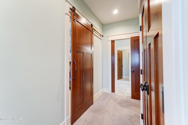 hall featuring a barn door and light colored carpet