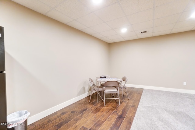 dining area featuring dark wood-type flooring and a drop ceiling