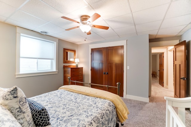 bedroom with light carpet, ceiling fan, and a drop ceiling