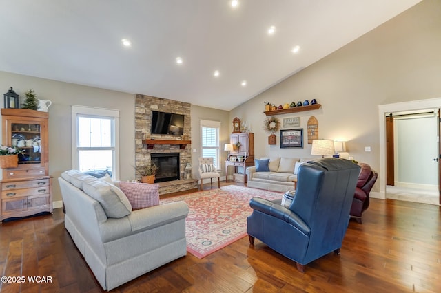 living room with dark hardwood / wood-style flooring, a stone fireplace, a barn door, and a healthy amount of sunlight