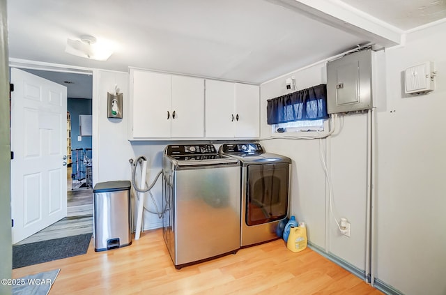 clothes washing area featuring electric panel, light hardwood / wood-style floors, and washing machine and dryer