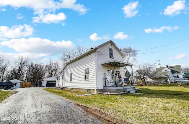 view of front of house featuring a garage, an outbuilding, and a front lawn