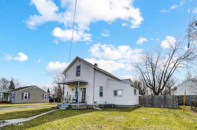 rear view of house featuring central air condition unit and a lawn