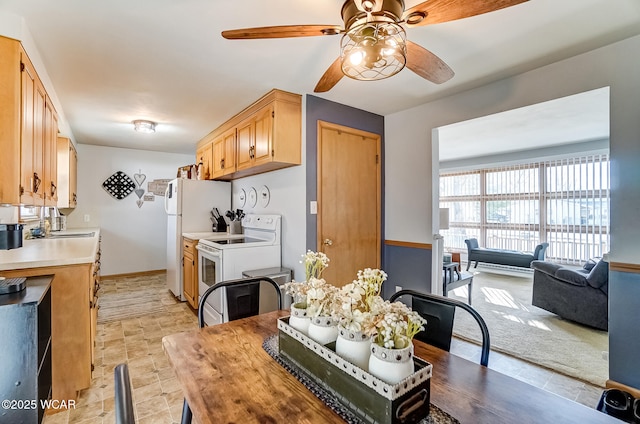 kitchen featuring light countertops, white appliances, a ceiling fan, and baseboards