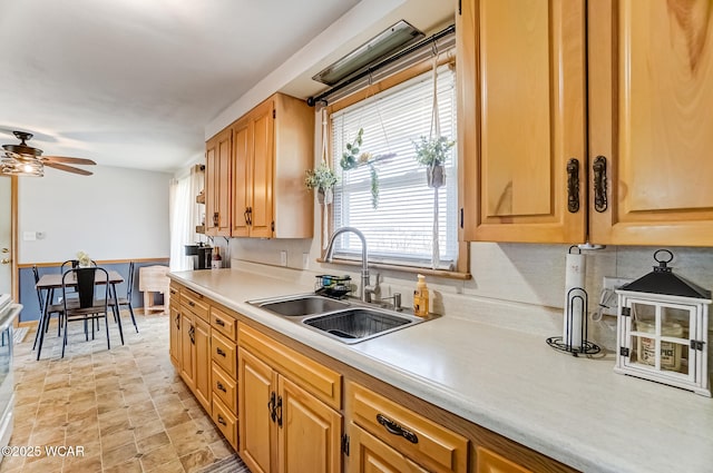 kitchen with light countertops, backsplash, a sink, and a ceiling fan