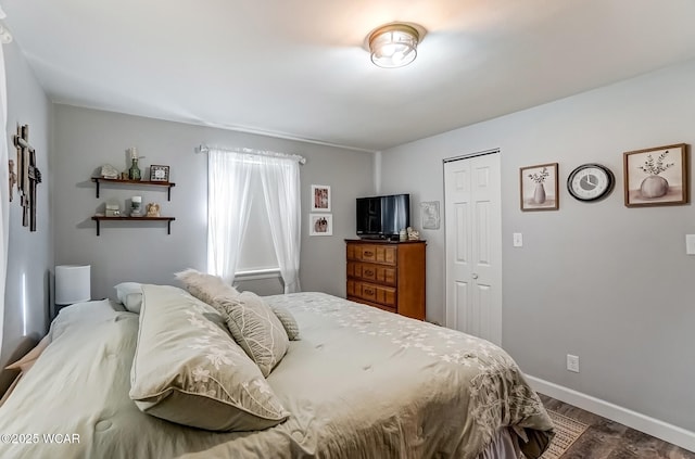 bedroom with a closet, dark wood finished floors, and baseboards