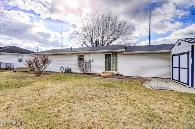 back of property with cooling unit, a lawn, and an outbuilding