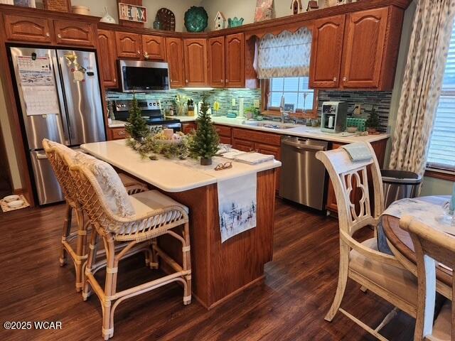 kitchen featuring dark wood finished floors, a sink, decorative backsplash, light countertops, and stainless steel appliances