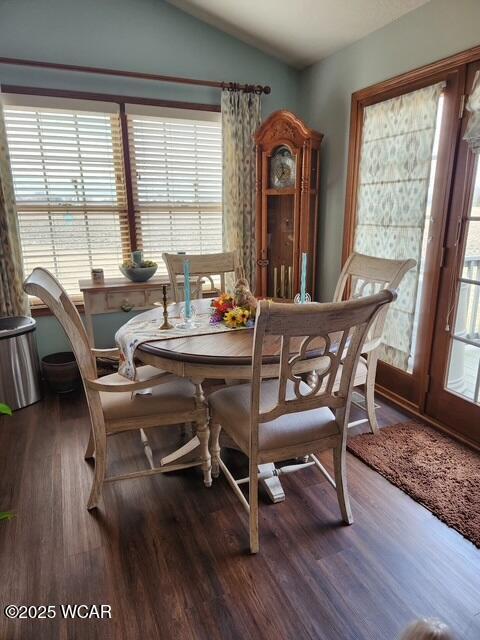 dining area featuring a healthy amount of sunlight, wood finished floors, and vaulted ceiling