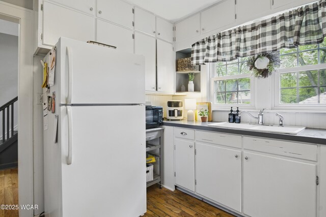 800 S Tyler St, Van Wert, OH 45891 - kitchen with freestanding refrigerator, a sink, dark wood-style flooring, white cabinets, and black microwave