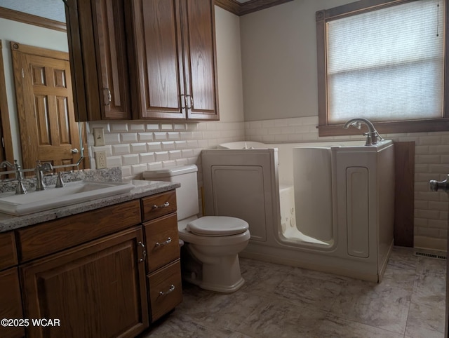 full bath with toilet, a wainscoted wall, a bathing tub, vanity, and tile walls