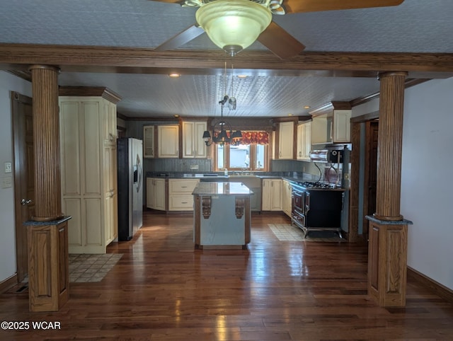 kitchen featuring cream cabinets, a center island, hanging light fixtures, stainless steel fridge with ice dispenser, and decorative columns