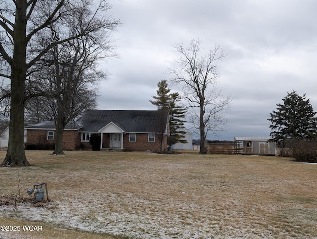 view of front of property featuring an outbuilding, a storage shed, fence, and brick siding