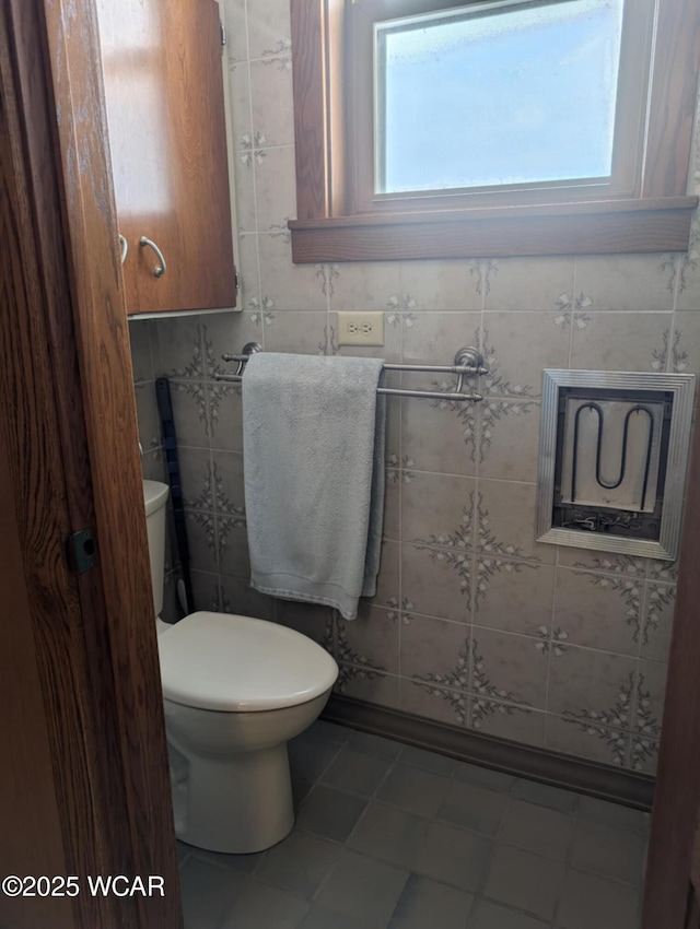 half bath with toilet and tile walls