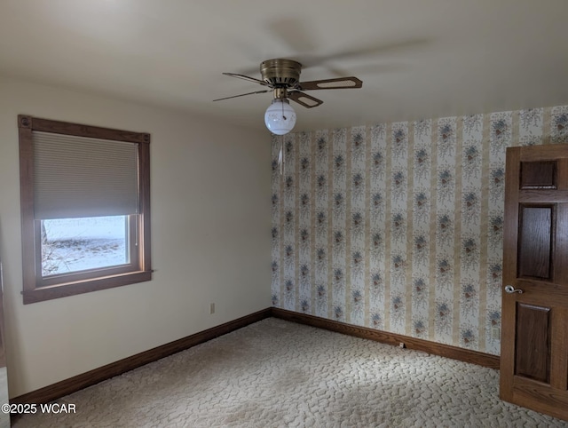 spare room with a ceiling fan, light carpet, and baseboards