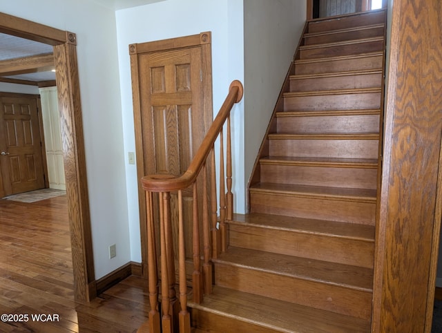 staircase featuring baseboards and wood finished floors