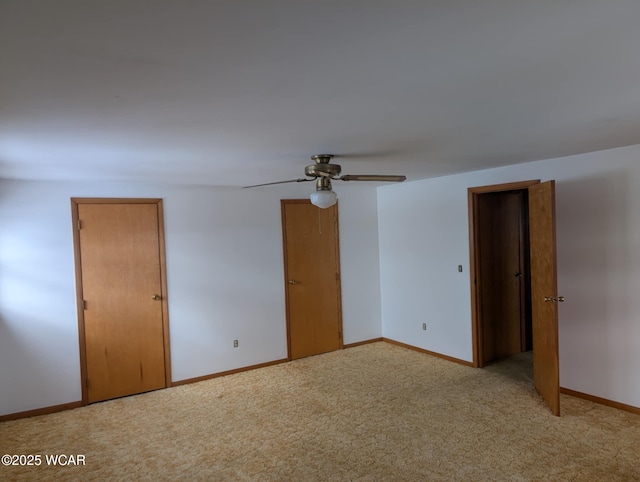 spare room with baseboards, a ceiling fan, and light colored carpet