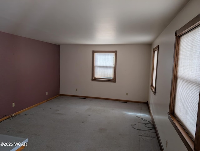 unfurnished room with visible vents, baseboards, and light colored carpet