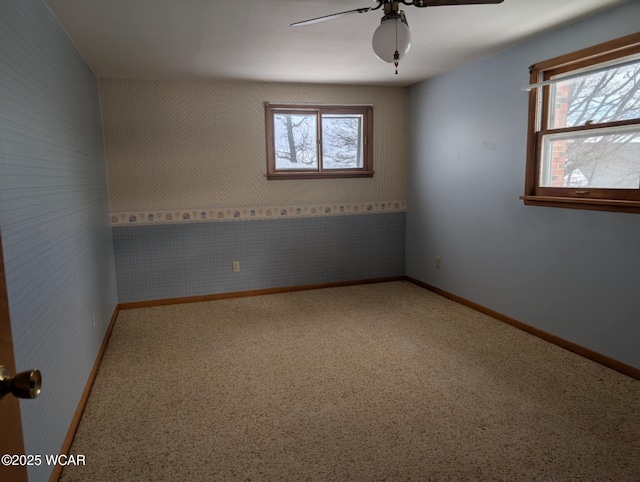 empty room featuring a ceiling fan, baseboards, and wallpapered walls